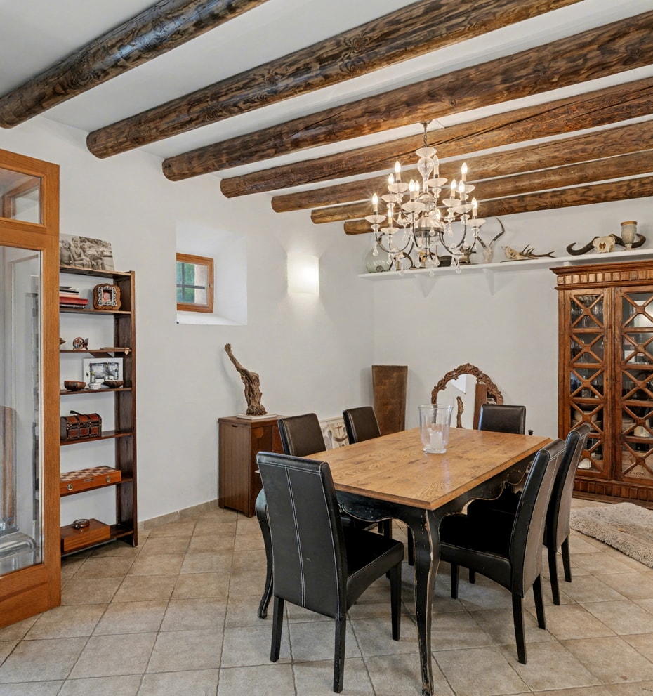 Rustic dining room with exposed wooden ceiling beams and terracotta floor tiles