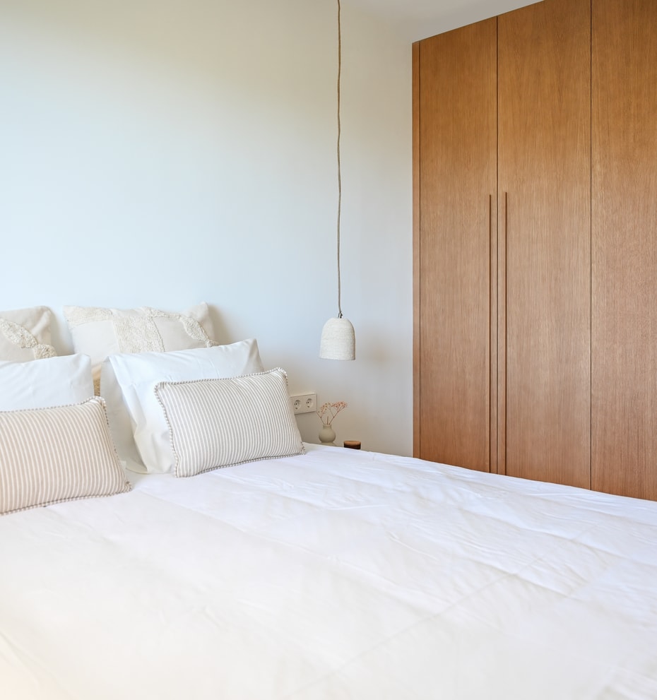 Guest bedroom with caramel linen bedding, oak low shelving beneath eaves, and minimalist Nordic styling