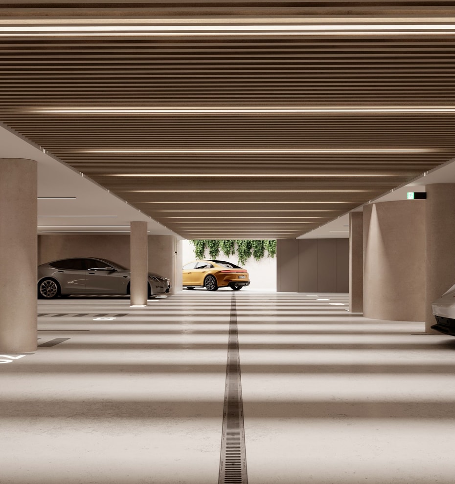 A modern, well-lit subterranean parking garage with concrete columns, linear ceiling lighting, and marked parking spaces.