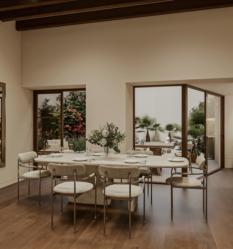 Dining table with eight chairs beside large windows and glazed doors overlooking a planted garden with bougainvillea and palms.