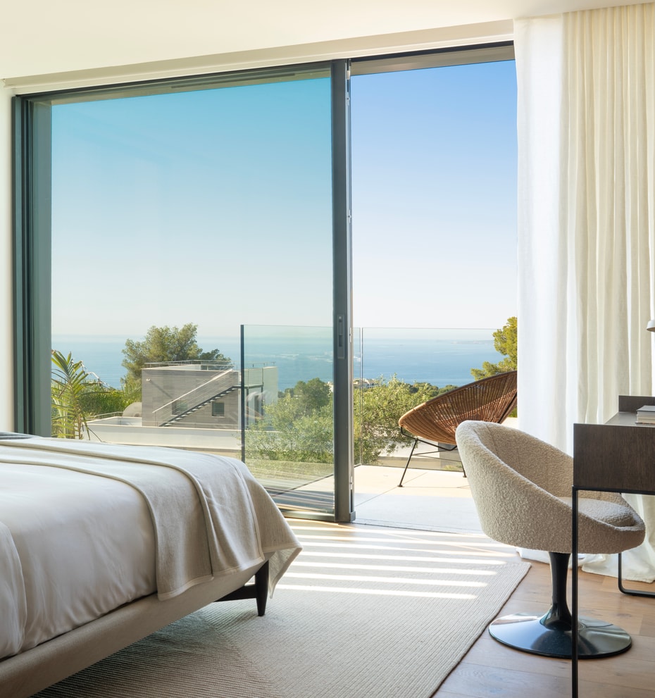 Master bedroom featuring a double bed, modern desk, and floor-to-ceiling windows overlooking the sea.